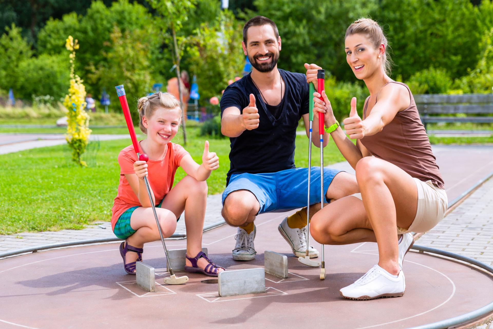 Family playing miniature golf on summer day