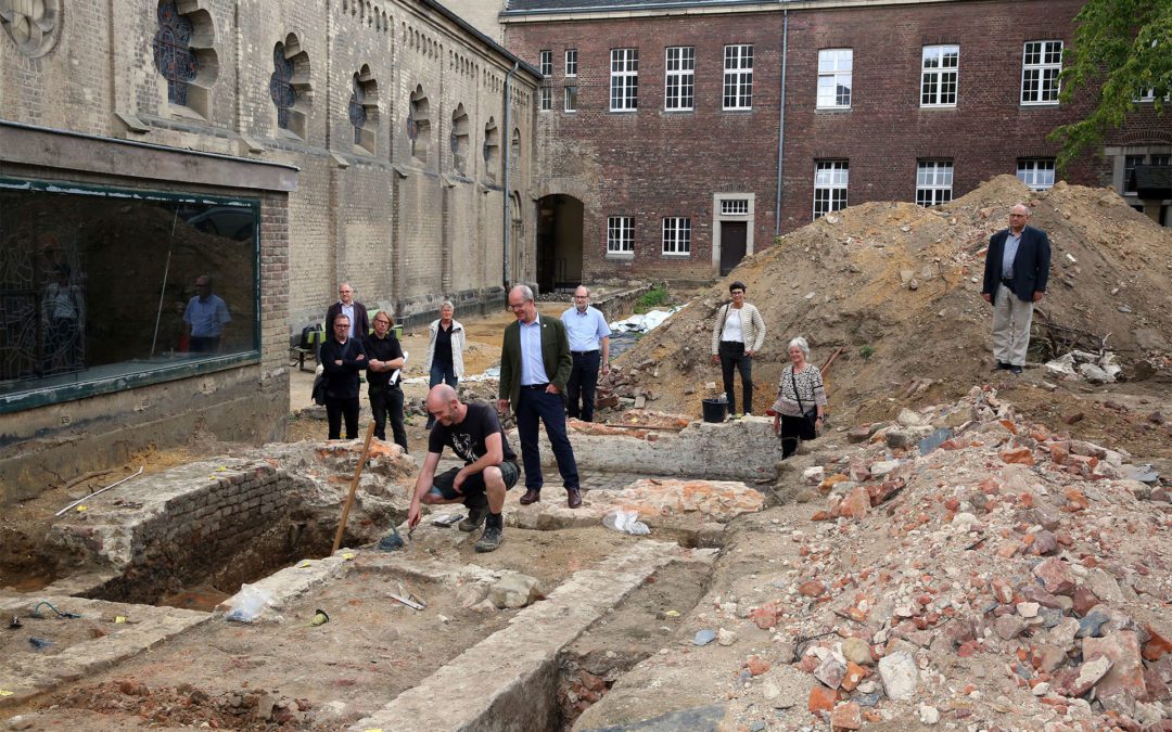 Archäologe D. Leahy zeigt Oberbürgermeister Reiners im Brunnenhof die Mauerreste des alten Kreuzgangs